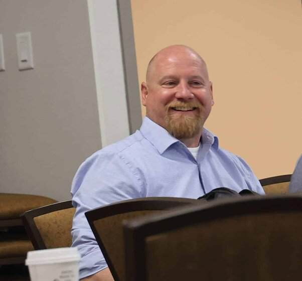 Dan Hale smiling and looking toward the room during a discussion.